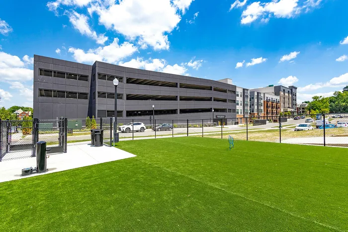 Vibrant outdoor area with lush green grass and modern parking structure, ideal for active urban living.