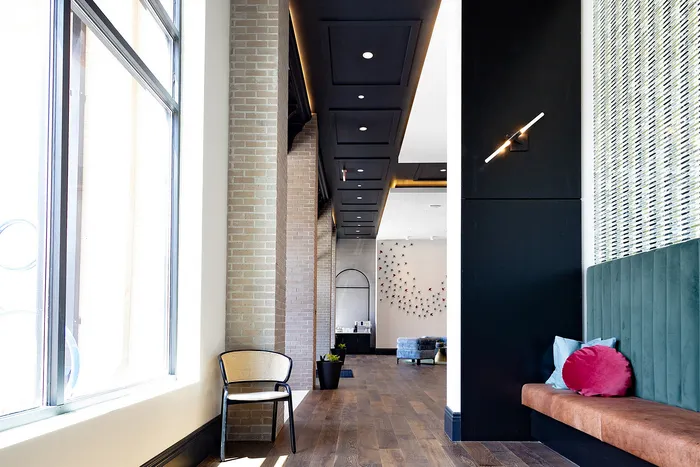 Modern apartment hallway with elegant wooden flooring, stylish seating, and vibrant wall decor, showcasing a perfect blend of comfort and contemporary design.
