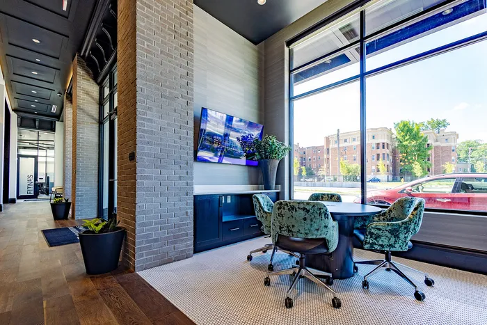 Modern office lounge with stylish seating, vibrant greenery, and a large window offering a scenic city view.