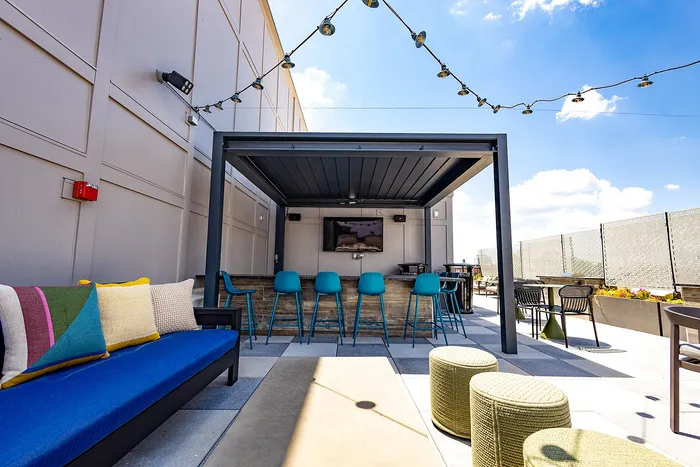 Chic rooftop patio with vibrant seating, modern bar area, and stunning sky views, perfect for entertaining.