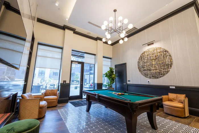 Elegant game room with a chic pool table, plush seating, and modern lighting, offering a stylish space for relaxation and entertainment.