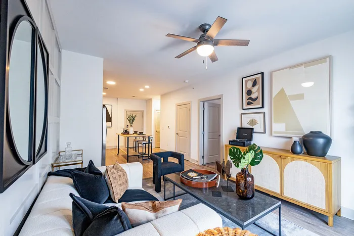 Chic and modern living room featuring a cozy sectional sofa, elegant decor, and a stylish ceiling fan, creating a warm and inviting atmosphere.