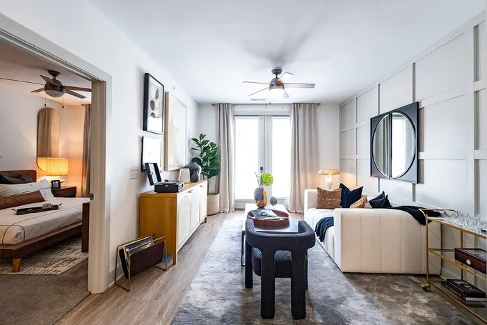 Elegant living room with modern decor, plush white sofa, and a cozy bedroom view, perfect for stylish urban living.