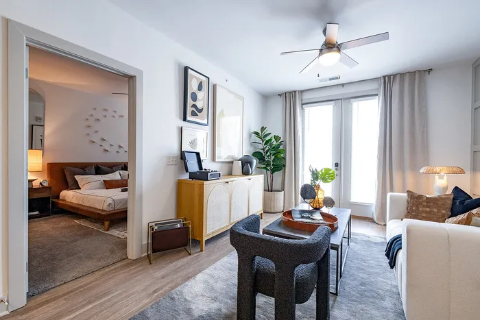 Contemporary urban living room with chic decor, cozy seating area, and access to a stylish bedroom. Vibrant indoor plant and modern artwork add flair.
