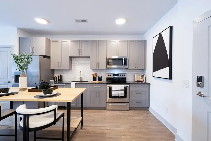 Modern kitchen with sleek gray cabinets, stainless steel appliances, and stylish dining area, offering a blend of functionality and elegance.