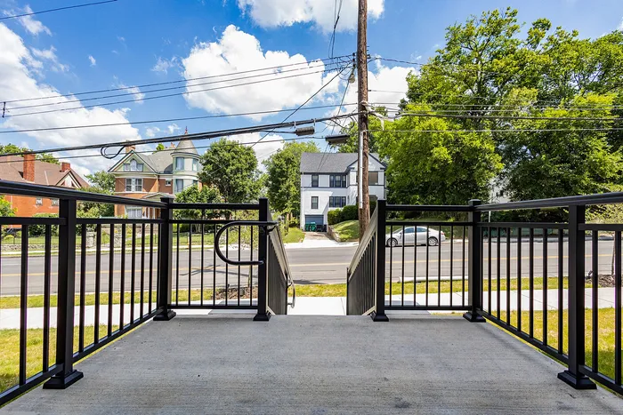 Scenic view from a charming porch overlooking a picturesque neighborhood with classic homes and lush greenery.