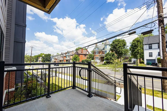 Charming balcony view showcasing a quaint neighborhood with beautiful, historic homes under a bright blue sky.