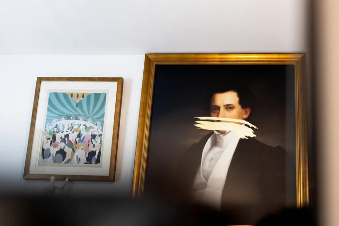 Chic interior showcasing elegant wall art, featuring a modern portrait with a bold artistic twist beside a vibrant illustration, framed in classic wooden frames.