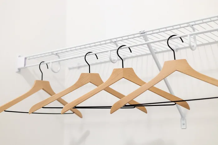 Elegant closet space with sleek wooden hangers and a sturdy white wire shelf.