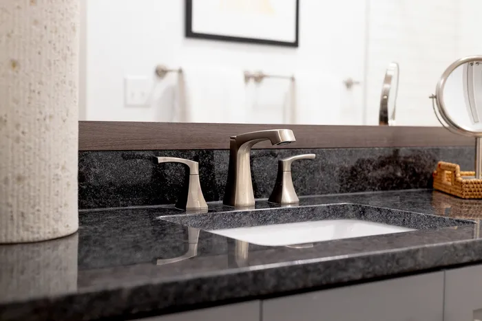Modern bathroom vanity with sleek chrome faucet and elegant granite countertop, perfect for luxury living.