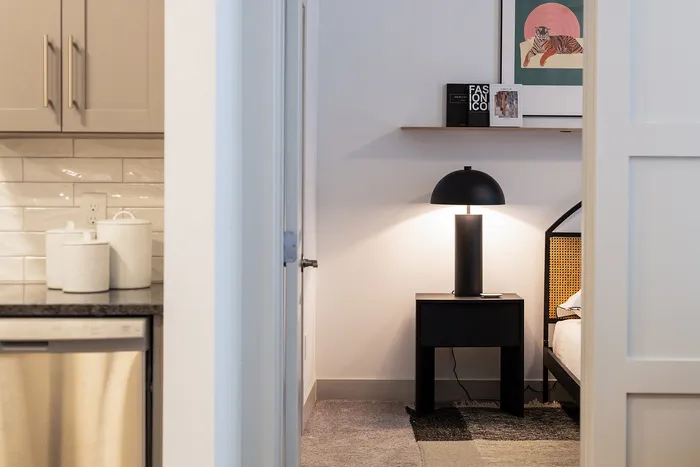 Contemporary apartment interior with a cozy lamp-lit corner, chic kitchen cabinetry, and elegant decorative accents.