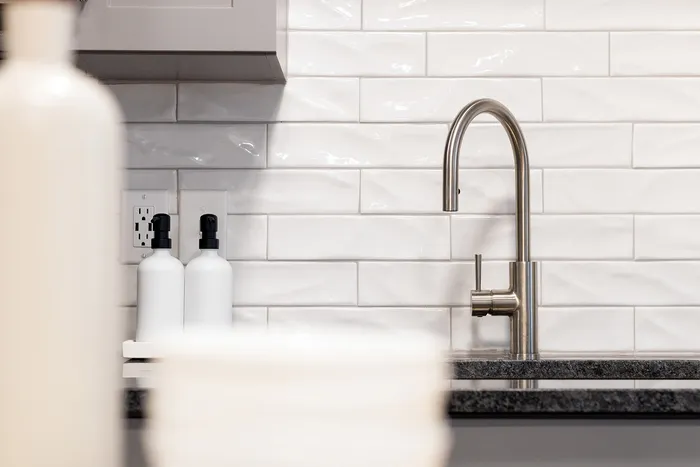 Modern kitchen detail with sleek stainless steel faucet and elegant white tiled backsplash.