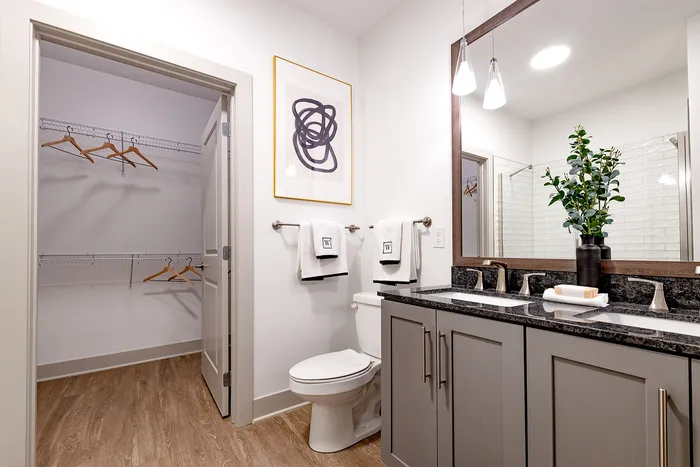 Elegant bathroom featuring a double vanity, modern fixtures, and a spacious walk-in closet, perfect for luxurious living.