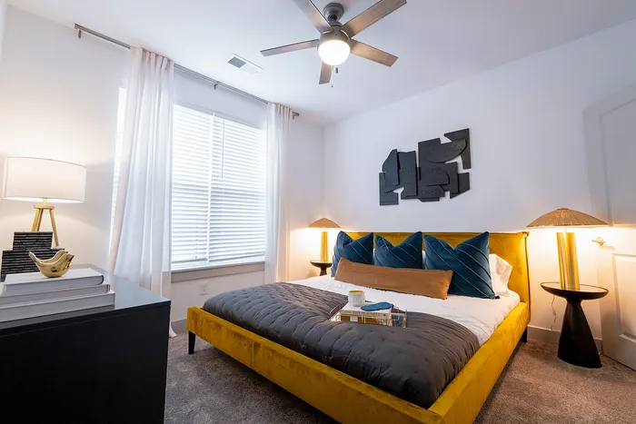 Modern bedroom with a luxurious velvet bed, stylish accent pillows, contemporary art, and elegant lighting.