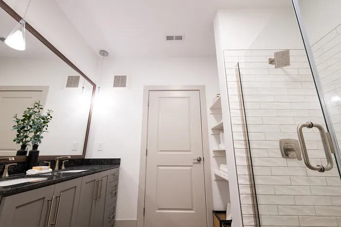 Elegant modern bathroom with stylish double sinks, sleek glass shower, and chic lighting.
