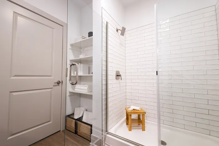 Sleek bathroom with glass-enclosed shower and built-in storage showcasing elegant tile work and modern fixtures.