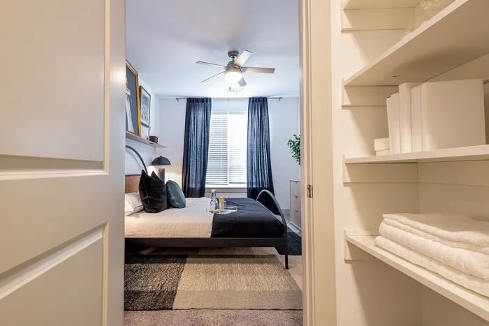 Inviting bedroom view featuring a cozy bed, elegant decor, and natural light streaming through large windows.