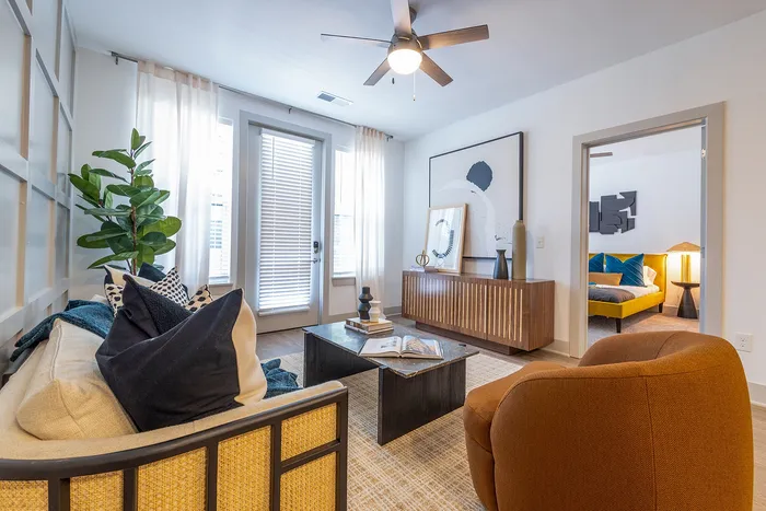 Chic living room featuring modern decor, cozy seating, and a view into a stylish bedroom.
