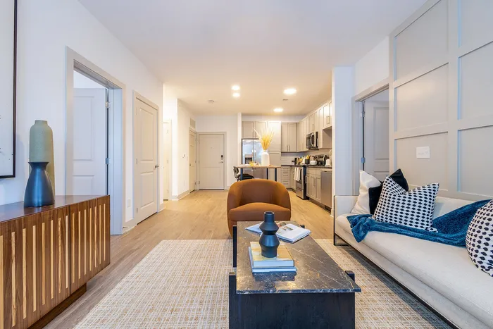 Contemporary apartment interior showcasing an open-concept kitchen and living room, stylishly furnished with modern decor and warm lighting.