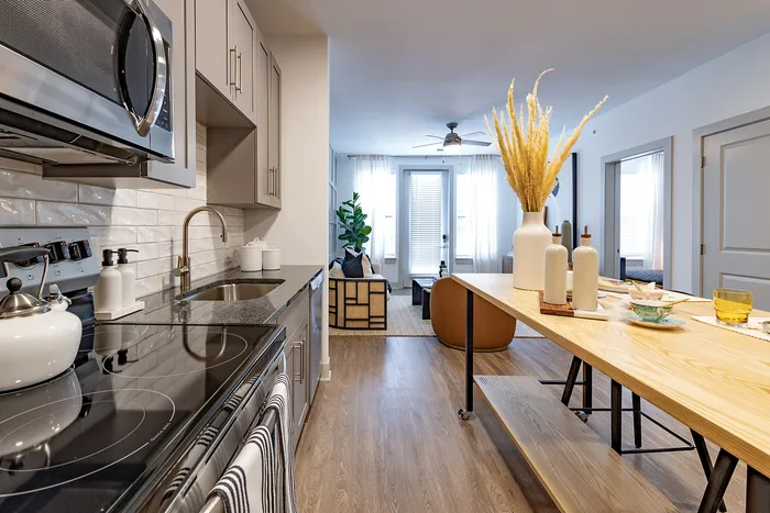 Modern open-concept apartment featuring a sleek kitchen with stainless steel appliances, elegant dining area, and a cozy living space with abundant natural light.
