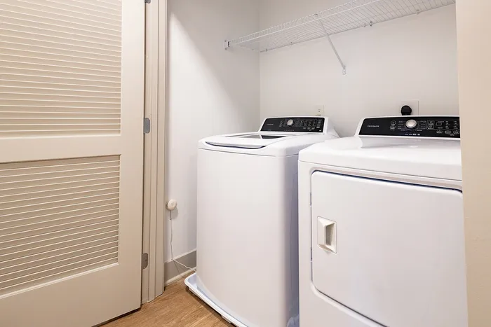 Modern laundry room featuring high-efficiency washer and dryer with ample shelving.