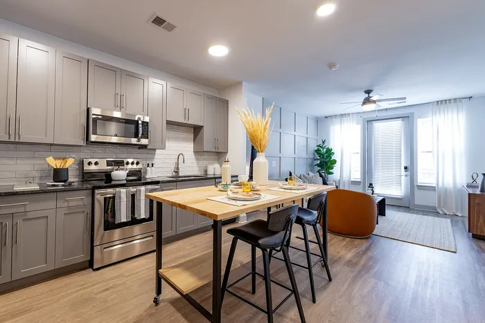 Contemporary open-concept kitchen and living area with sleek gray cabinetry, modern appliances, and a stylish breakfast bar, perfect for entertaining in a bright, airy space.