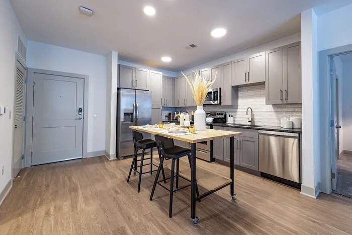 Modern kitchen with sleek gray cabinets, stainless steel appliances, and a stylish wooden island perfect for entertaining.