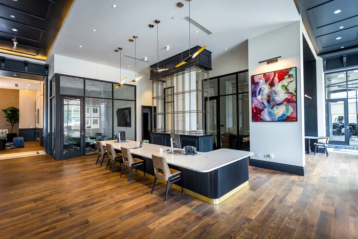 Spacious and modern apartment lobby with stylish wooden flooring, contemporary artwork, and elegant seating area under chic lighting fixtures.