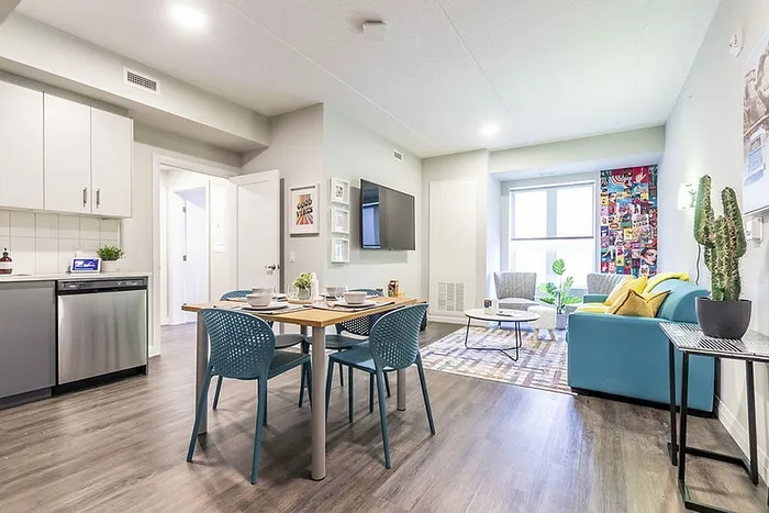 Modern apartment showcasing an open-concept living area with a vibrant seating arrangement, stylish dining space, and sleek kitchen appliances.