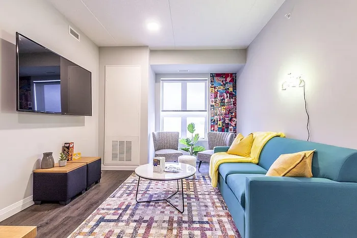 Inviting living room with modern decor, featuring a vibrant blue sofa, cozy seating area, and wall art, ideal for relaxation.