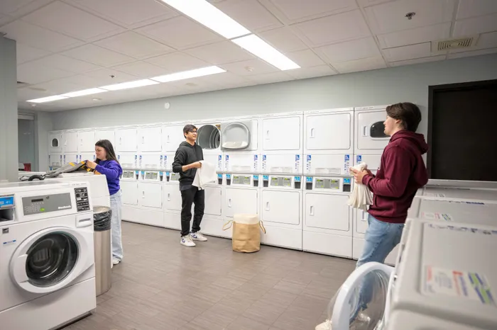 Modern communal laundry room with sleek washers and dryers, featuring a bright, inviting atmosphere and friendly interaction among residents.