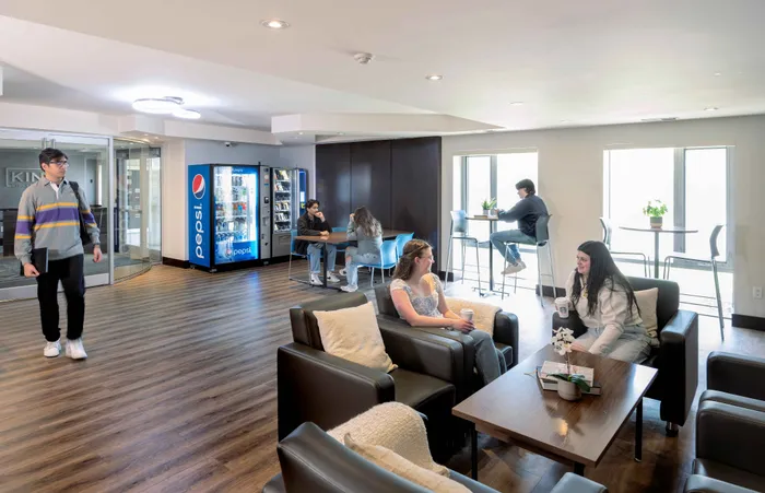 Bright and inviting lounge area with vending machines, comfortable seating, and large windows, creating a perfect spot for relaxation and socializing.