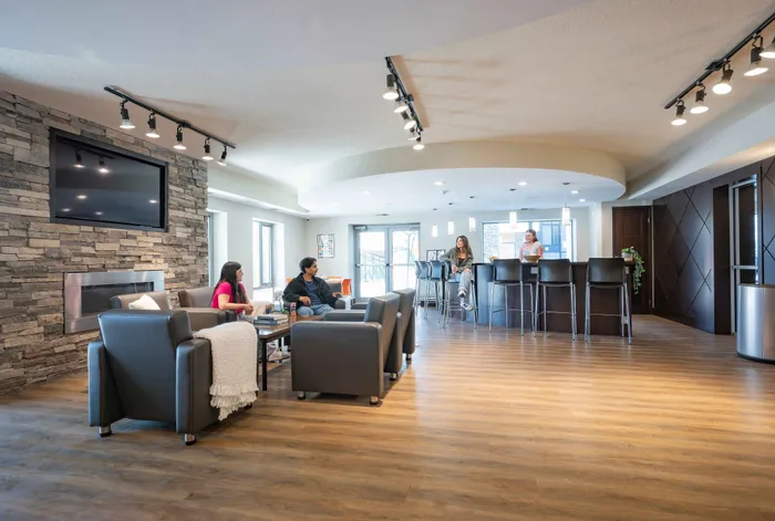 Modern apartment common area with stylish seating, stone fireplace, and a sleek bar, perfect for socializing and relaxation.