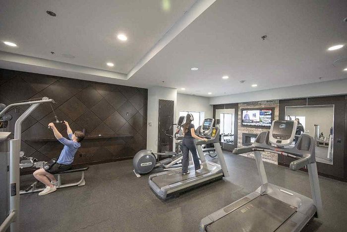 Modern fitness center with state-of-the-art treadmills, sleek weight machine, and a cozy television lounge area, perfect for a dynamic workout experience.