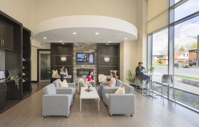 Modern communal lounge with sleek furniture, large windows offering natural light, and a cozy seating area with TV.