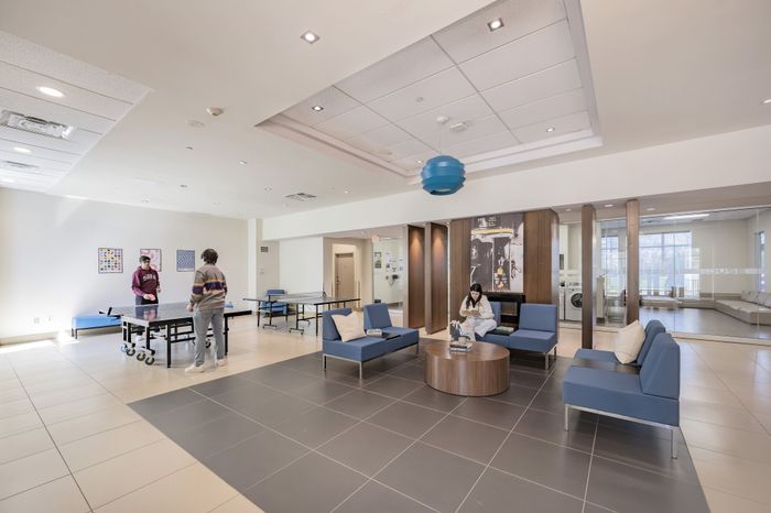 Bright and welcoming common area with stylish blue seating, table tennis, and modern decor, perfect for relaxation and social gatherings.