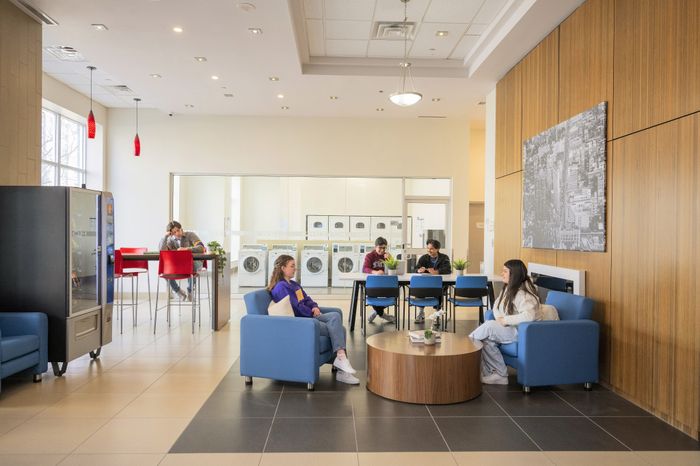 Modern communal lounge with vibrant seating, bright lighting, and an inviting laundry facility in the background.