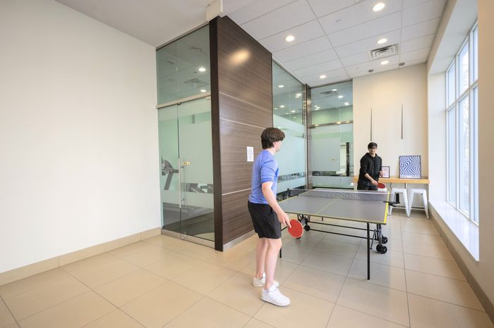 Modern recreation room featuring a ping pong table and large glass windows for natural light.