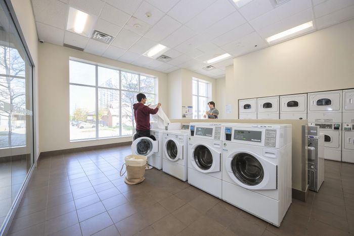 Bright and modern laundry room with natural light, featuring multiple front-load washers and dryers, creating a convenient and inviting space.