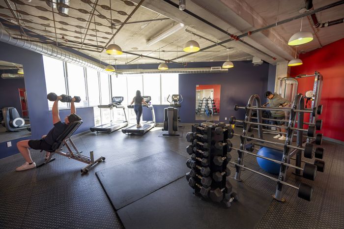 Contemporary fitness center with modern equipment, featuring large windows for natural light, weight racks, and cardio machines for an energizing workout experience.