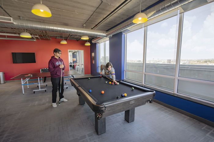 Modern recreation room with a pool table, playful atmosphere, and large windows offering stunning city views.