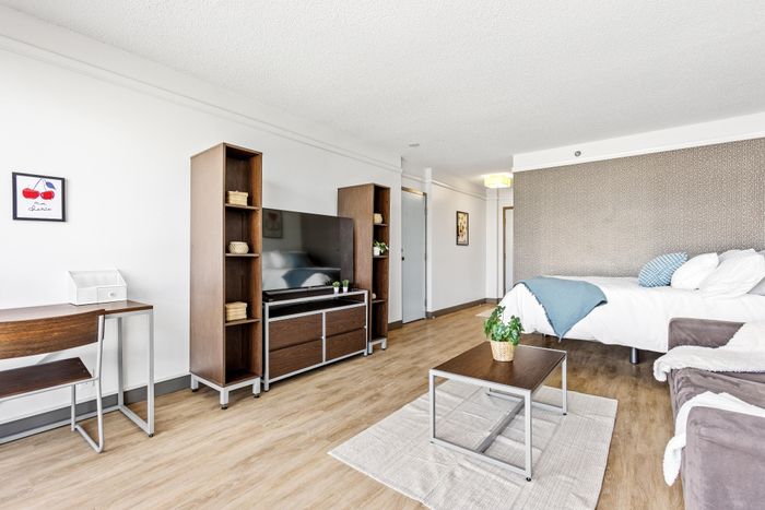 Chic studio apartment with modern furnishings, featuring a cozy bed, sleek entertainment center, and a charming workspace.
