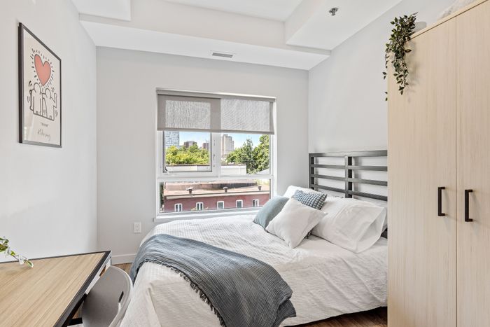 Bright and cozy bedroom with modern decor, featuring a large window offering a refreshing cityscape view.