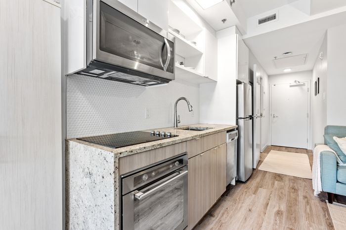 Modern kitchen design with sleek stainless steel appliances, granite countertops, and elegant light wood cabinetry.