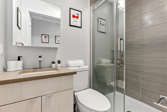 Contemporary bathroom featuring sleek cabinetry, modern fixtures, glass shower, and stylish wall art for a chic urban vibe.
