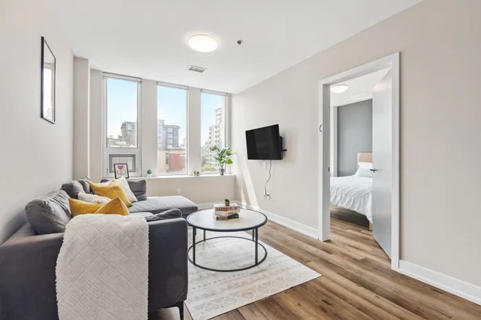 Contemporary apartment living room with cozy gray sofa, stylish decor, and large windows offering abundant natural light.