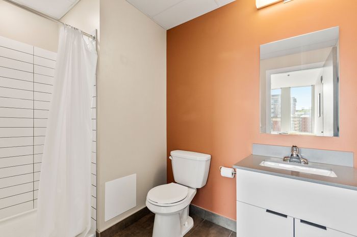 Modern bathroom with sleek white fixtures, a vibrant accent wall, and a spacious shower area.