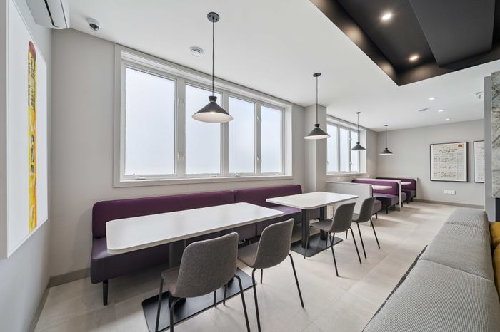 Modern dining area with ample natural light, elegant lighting fixtures, and sleek purple seating for a stylish ambiance.