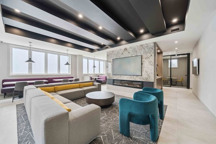 Modern lounge area with elegant marble fireplace, stylish seating, and abundant natural light from large windows.