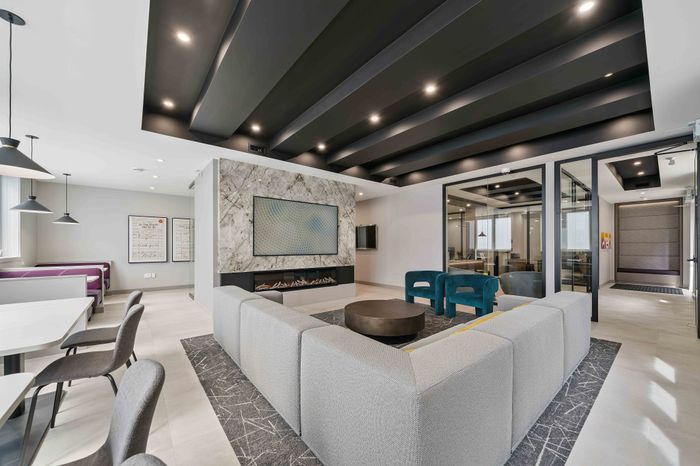 Contemporary lounge area with luxurious seating, modern decor, and a cozy fireplace in a spacious, well-lit apartment.